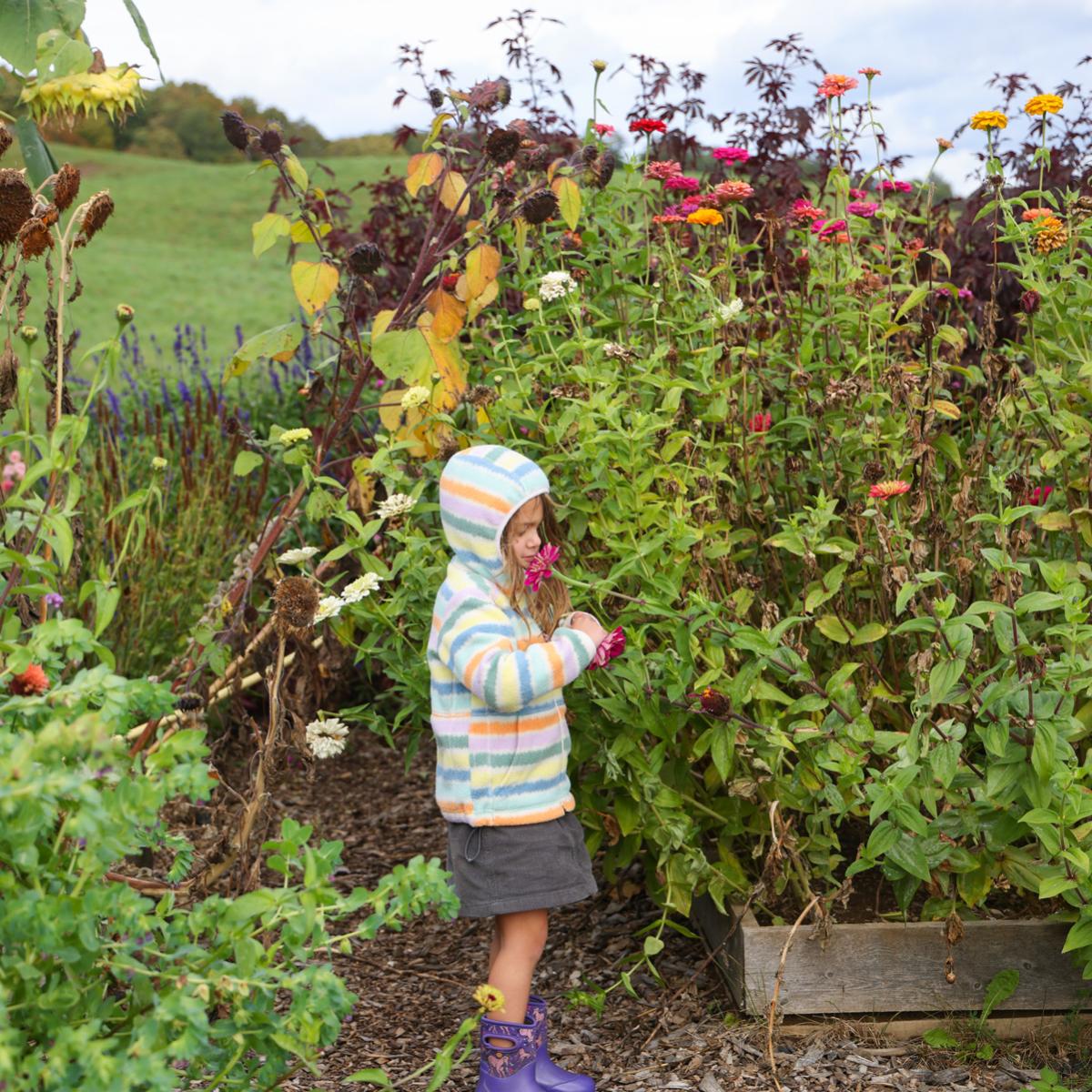 a child stands in a flower garden