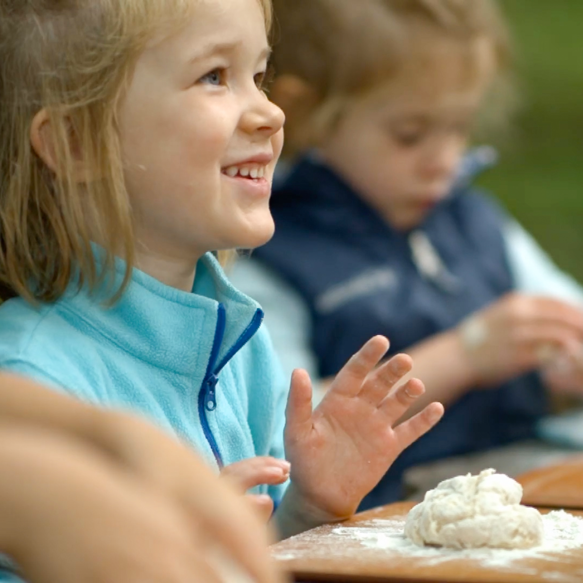 a student smiles as she prepares to knead dough.