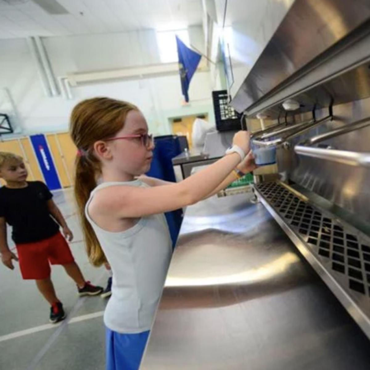 a student dispenses milk from a stainless steel machine a student dispenses milk from a stainless steel machine
