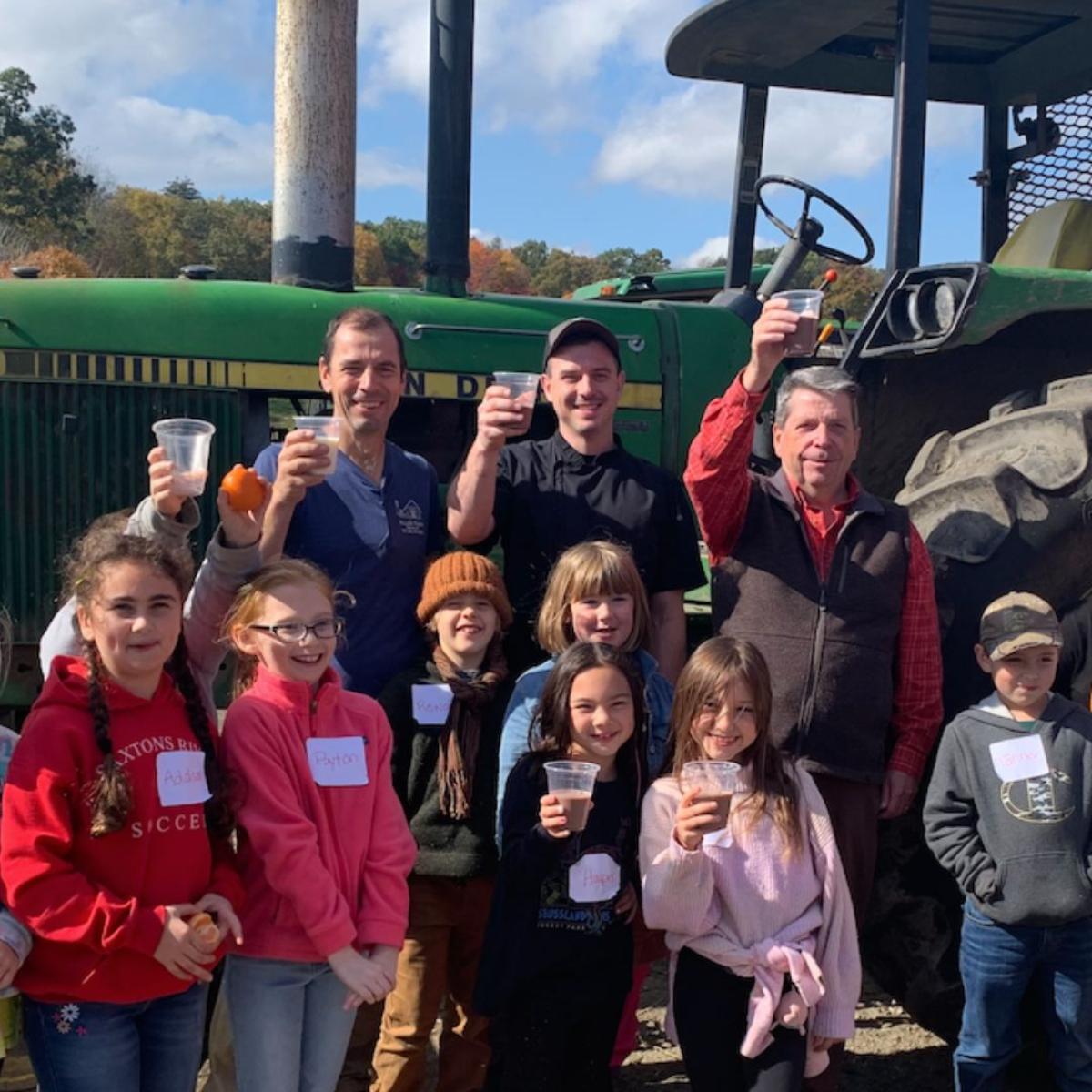 kids and adults stand near a tractor at Miller Farm