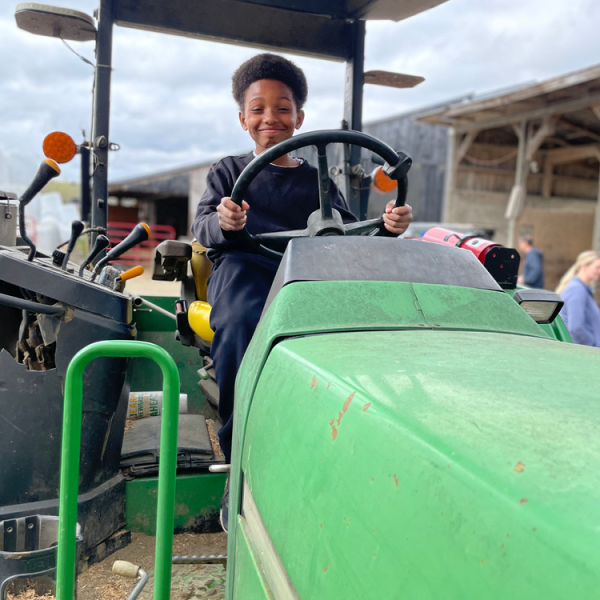 a student smiles from the drivers seat of a tractor a student smiles from the drivers seat of a tractor