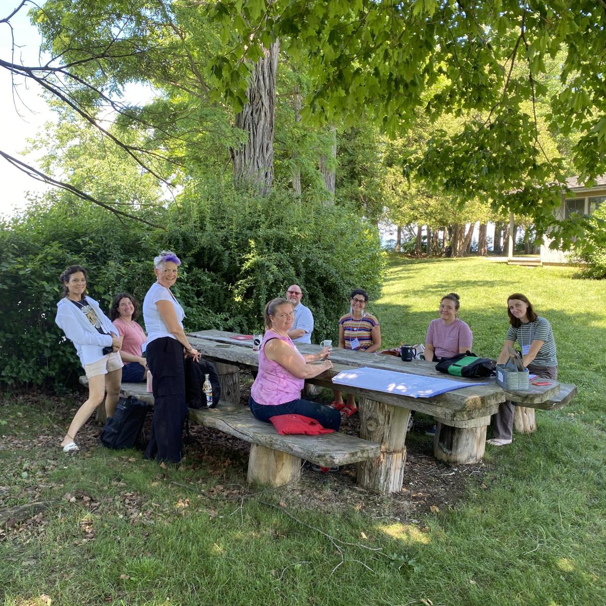 a group of adults work outdoors at a picnic table a group of adults work outdoors at a picnic table