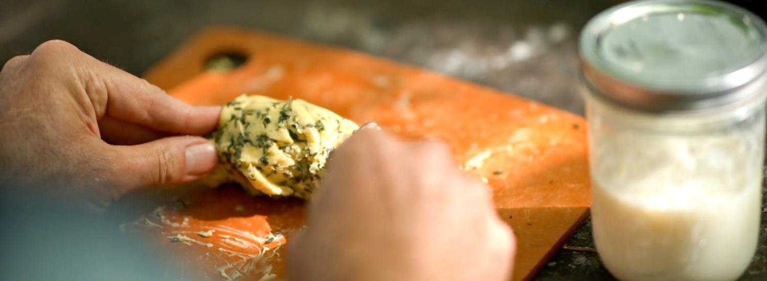 Compound butter being shaped into a log by hand.